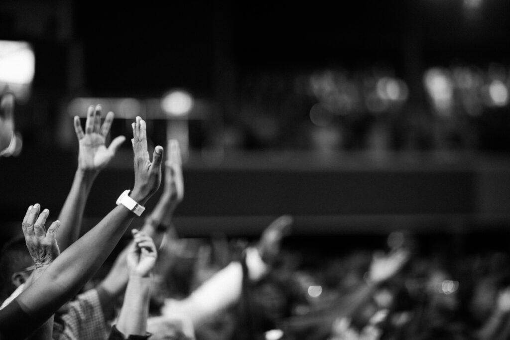 pexels-photo-2014773-2014773 Black and white image of audience with hands raised, capturing concert energy.