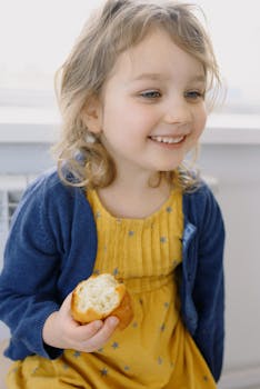 pexels-photo-4048691-4048691 Happy child in a yellow dress enjoying a snack, radiating innocence and joy.